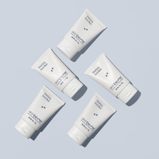 Flat lay of multiple Skinbetter Science Detoxifying Scrub Mask 20oz tubes on a light gray background, showcasing sleek white packaging