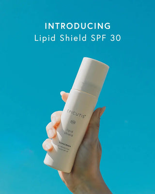 Hand holding a bottle of Epicutis Lipid Shield SPF 30 against a blue background