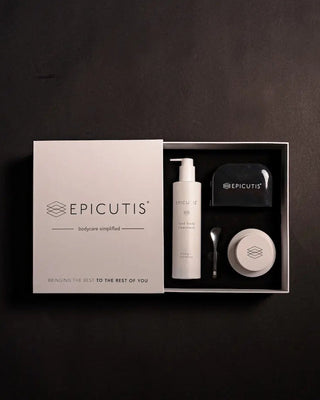 Epicutis skincare gift set in a white box, featuring a white bottle, a black jar, and a small round tin, displayed on a dark textured background.