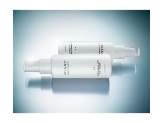Two white VIVANT skincare pump bottles with blue accents, displayed on a reflective light blue surface.