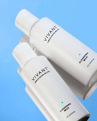 Two white Vivant Cleansing Milk bottles of different sizes arranged diagonally on a light blue background.