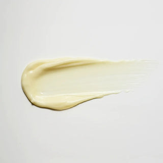 A thick, creamy swatch of pale yellow cosmetic cream or lotion smeared horizontally on a clean, light off-white background.