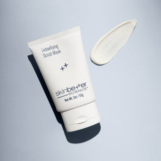 Skinbetter Detoxifying Scrub Mask 2oz tube on a blue background with product smear.